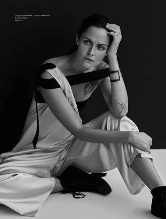 Monochrome portrait of a seated woman wearing a draped top and wide pants with dark shoes, styled by Anna Katsanis.