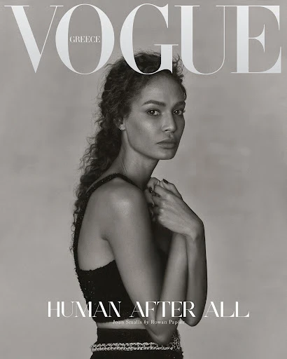 Vogue Greece cover featuring a woman with curly hair in a black two-piece outfit, posing with her hands near her face in a studio setting.