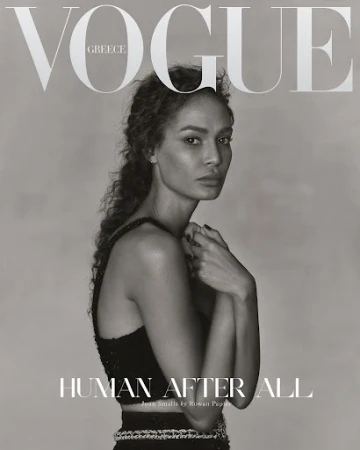 Vogue Greece cover featuring a woman with curly hair in a black two-piece outfit, posing with her hands near her face in a studio setting.