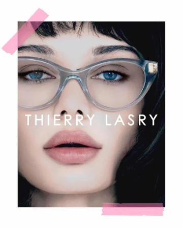 Close-up portrait of a woman wearing transparent cat-eye glasses and styled by Anna Katsanis against a dark background