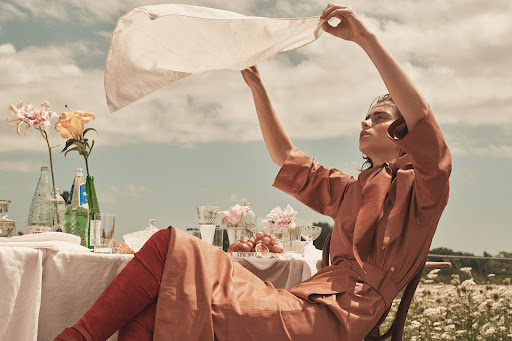 Model holding white cloth overhead at outdoor picnic table styled by Anna Katsanis