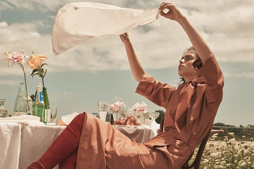 Model holding white cloth overhead at outdoor picnic table styled by Anna Katsanis