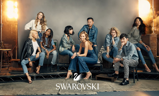 Group shot of nine diverse adults sitting and standing in a photo studio setting, wearing denim and casual attire with bright studio lighting.