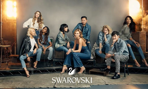 Group shot of nine diverse adults sitting and standing in a photo studio setting, wearing denim and casual attire with bright studio lighting.