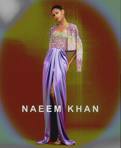 Elegant fashion shot: a woman in a glittering top and purple skirt poses against a painted backdrop, showcasing high-fashion glamour.