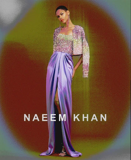 Elegant fashion shot: a woman in a glittering top and purple skirt poses against a painted backdrop, showcasing high-fashion glamour.