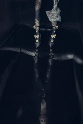Model legs in patterned black tights and pumps with bows reflected on a dark glossy floor styled by Anna Katsanis