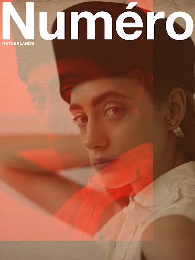 Close-up portrait of a woman wearing a dark cap and white collared shirt with red overlay branding for Numero Netherlands.
