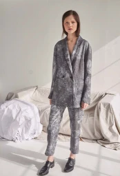 Model wearing a grey patterned suit and black leather shoes standing in a bright studio space