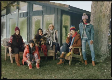 Group of six women posing outdoors in winter clothing in front of a dark green house styled by Annina Mislin.