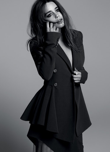 Black and white portrait of a woman in a stylish dark jacket with an asymmetrical hem, posing against a neutral grey background.