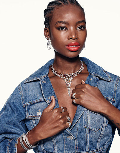 Portrait of an adult woman with red lipstick and silver jewellery including necklace, earrings and rings wearing a denim jacket.