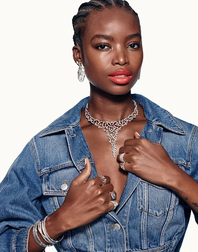 Portrait of an adult woman with red lipstick and silver jewellery including necklace, earrings and rings wearing a denim jacket.