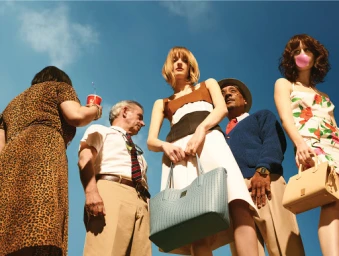 Low-angle shot of a diverse group of models standing against a clear blue sky, styled by Daniel Edley.