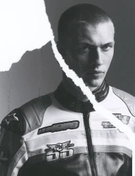 Monochrome portrait of a young man wearing a leather motorcycle jacket, partially obscured by a diagonal torn paper overlay.