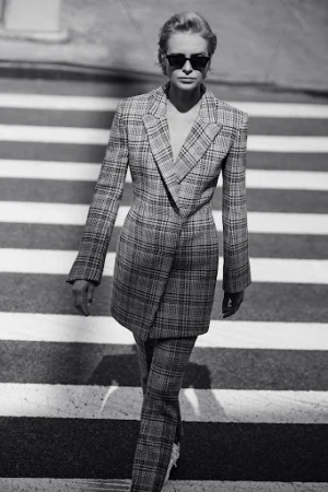 Model in plaid suit and sunglasses walking across a crosswalk styled by Deborah Watson