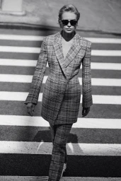 Model in plaid suit and sunglasses walking across a crosswalk styled by Deborah Watson