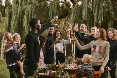 Group of diverse people raising glasses in a toast outdoors at a long dining table styled by Deborah Watson.