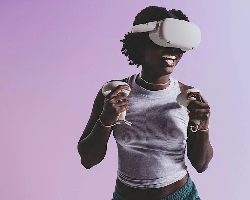 Woman experiencing virtual reality using a VR headset and controllers, smiling against a gradient purple background, studio lighting.