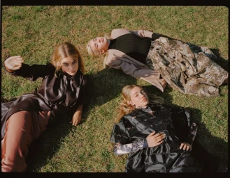 Three female models lying on green grass outdoors styled by Heather Rest