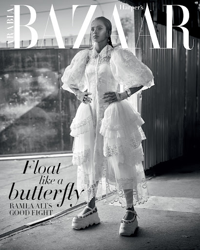Black and white fashion editorial shot of Ramla Ali on Harper's Bazaar Arabia cover in a white tiered dress with puff sleeves and platform shoes.