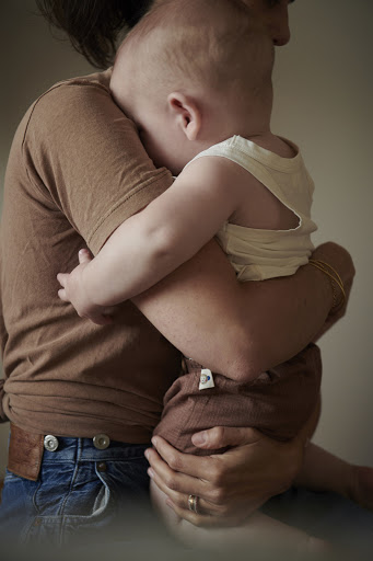 Close-up of parent holding a baby indoors, showcasing a tender moment with soft lighting, casual clothing, and a focus on familial love.