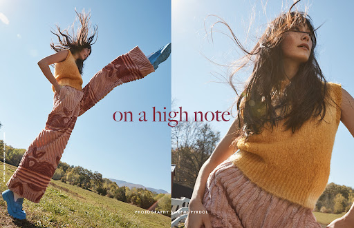 A fashion shot features a long-haired young adult woman in a yellow top and patterned pants in an outdoor, sunny, rural setting.