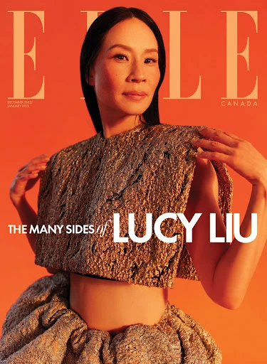 Lucy Liu on the cover of ELLE Canada, October 2022/January 2023 issue. She is in a gold textured garment against an orange backdrop.