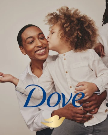 Dove ad featuring a mother and her child with curly hair. The son is kissing the mother on the cheek with a neutral background.