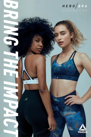Two athletic women in sports bras and leggings pose for a fitness campaign. One woman has afro hair, and the other has blonde hair.