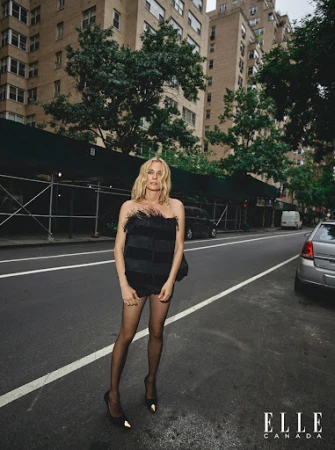 Blonde woman standing on a city street wearing a black feathered top and black heels, styled by Liz Mcclean.