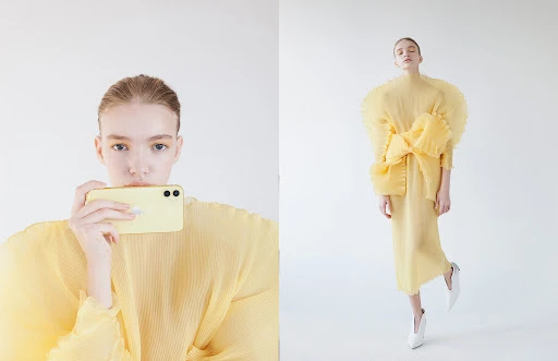 Woman in yellow dress holds a yellow smartphone in a full studio shot with a white background, showcasing a modern fashion aesthetic.