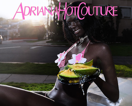 A dark-skinned woman poses in a pink swimsuit holding fruit on a glass plate outdoors in a sunlit, suburban setting, with graphic text.