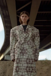 Model in structured plaid coat standing under a concrete overpass bridge, styled by Mari Siviakova.
