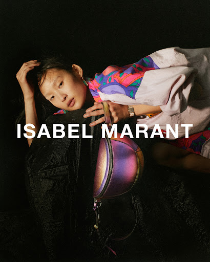 Fashion editorial: Young Asian model poses with an iridescent handbag against a black background, wearing a colorful patterned jacket.