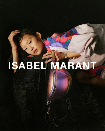 Fashion editorial: Young Asian model poses with an iridescent handbag against a black background, wearing a colorful patterned jacket.