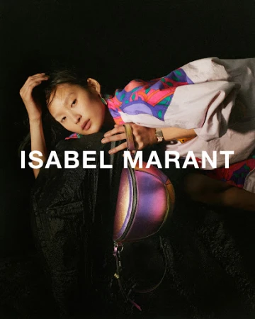 Fashion editorial: Young Asian model poses with an iridescent handbag against a black background, wearing a colorful patterned jacket.