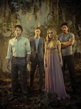 Group portrait of four actors standing outdoors in a dark, atmospheric wooded setting with hanging Spanish moss.