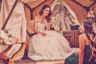 Bride in a white strapless lace wedding dress reading a letter inside a canvas tent with floral arrangements.