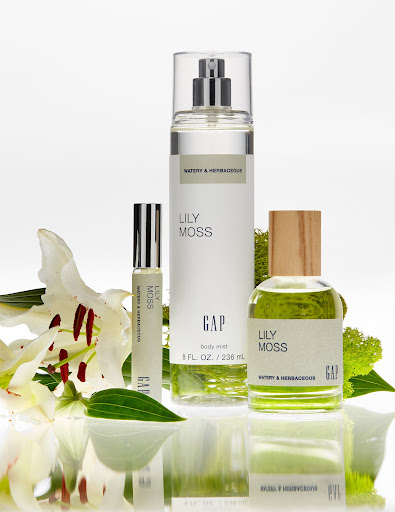Three GAP Lily Moss fragrance bottles are displayed with white lily flowers and greenery, set against a bright white background.