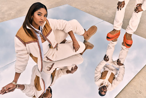 A woman and another person stand on a reflective surface wearing matching outfits with fleece jackets and UGG footwear.