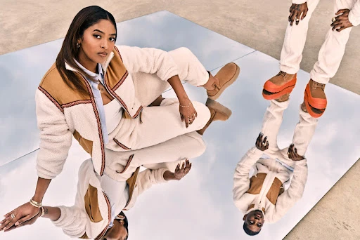 A woman and another person stand on a reflective surface wearing matching outfits with fleece jackets and UGG footwear.