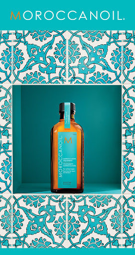 Moroccanoil bottle on a shelf against teal background and decorative tile border featuring floral patterns, showcasing hair care products.