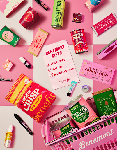 Overhead shot of Benefit cosmetics in a pink shopping basket on a pink and white checkered background for beauty advertising.