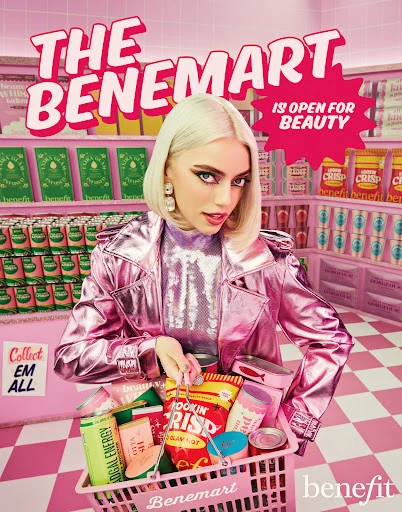 Woman with platinum blonde hair, wearing a shiny pink jacket, holding a shopping basket with beauty products in a pink beauty aisle.