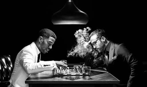 Two men playing chess in a black and white studio setting, with one smoking and sipping whiskey. The atmosphere is intense and focused.