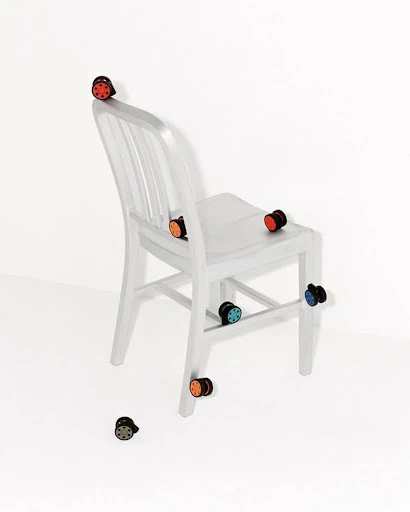 White chair adorned with colorful circular knobs against a clean white backdrop, creating a playful and modern design.
