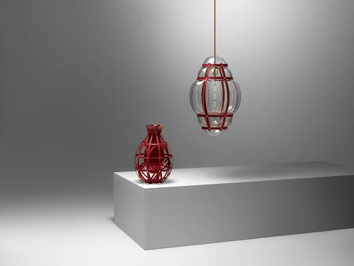 Still life featuring a transparent pendant light and a vase, both with red geometric frames, sitting atop a white rectangular pedestal.