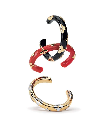 Three Louis Vuitton Monogram cuff bracelets in black, red, and gold tones featuring a floral design against a white background.