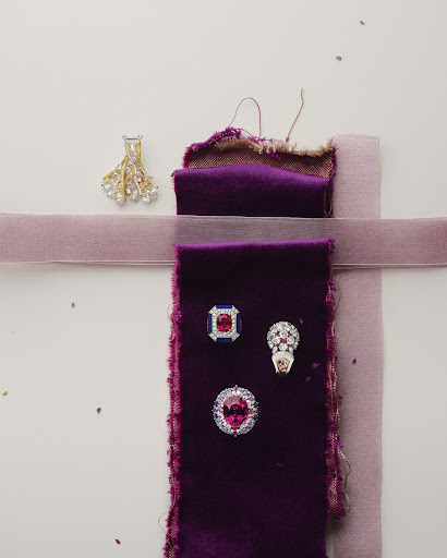 Four rings displayed on dark and light purple velvet ribbons, isolated on a white surface, flat lay jewelry product shot.